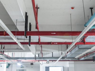 Fire protection sprinkler system with red pipes is placed to hanging from the ceiling
